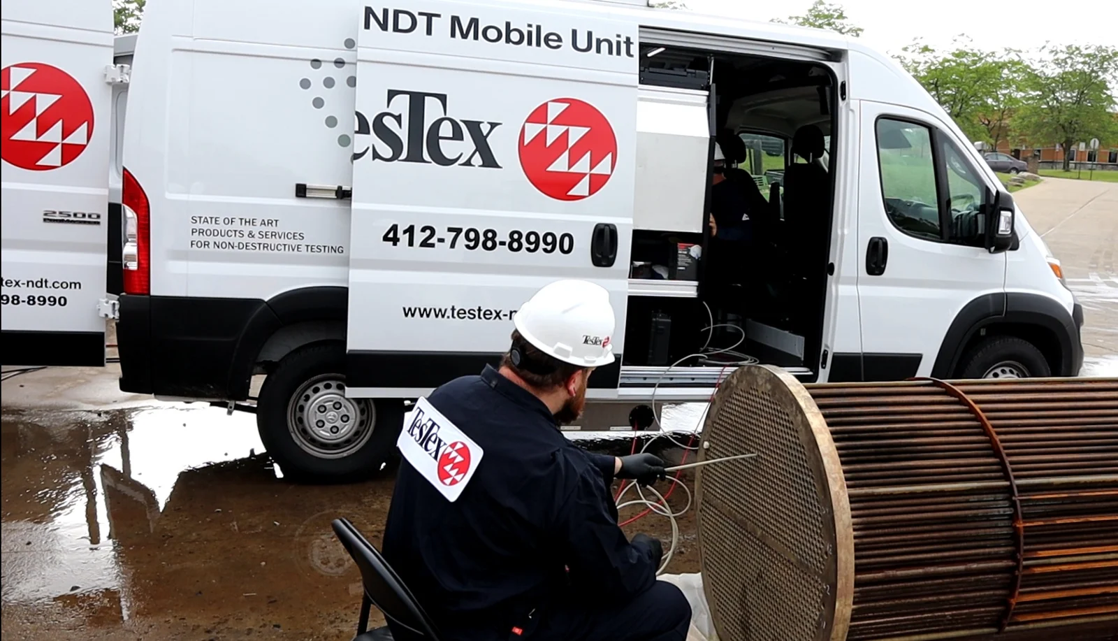 TesTex technician inspecting a heat exchanger beside the SuperVan mobile NDT lab
